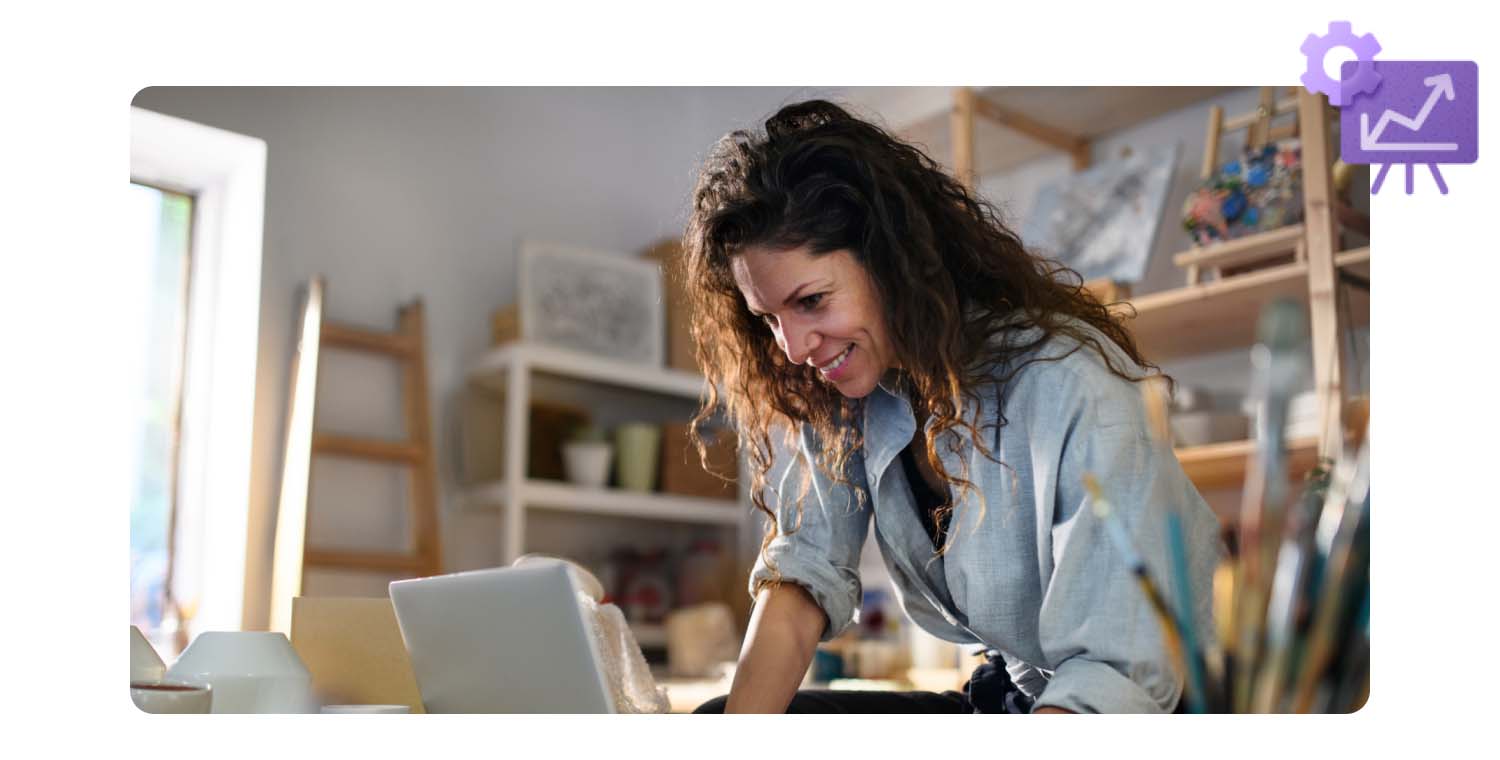 A woman at her art studio working on her personal laptop computer.