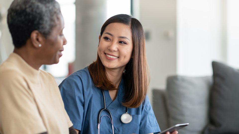 A nurse sits with their patient and consults.