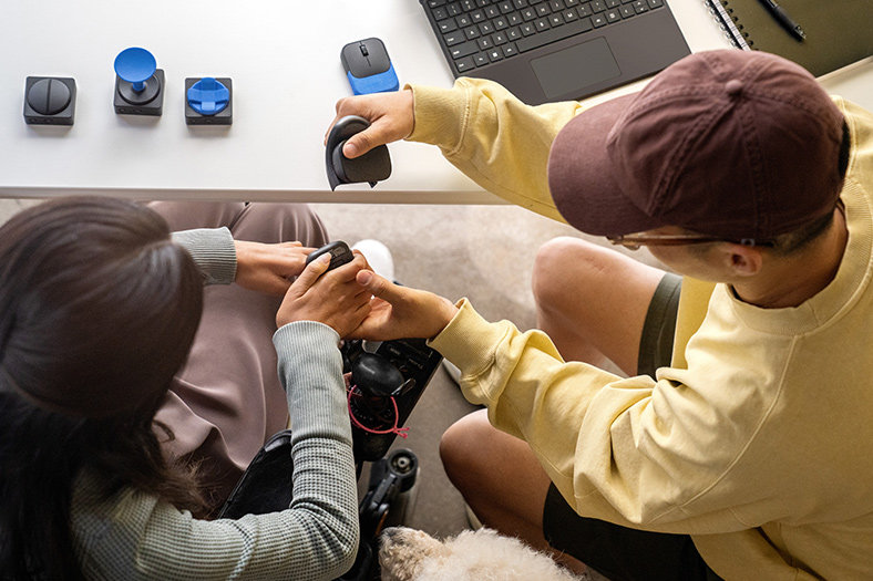 An occupational therapist works with his client to use Microsoft adaptive accessories to use a Surface Pro 9 device.