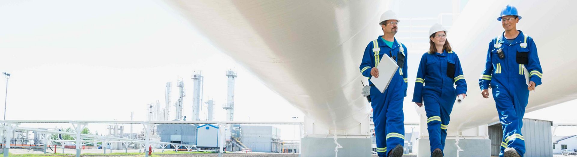 Workers walking below tanks at gas plant