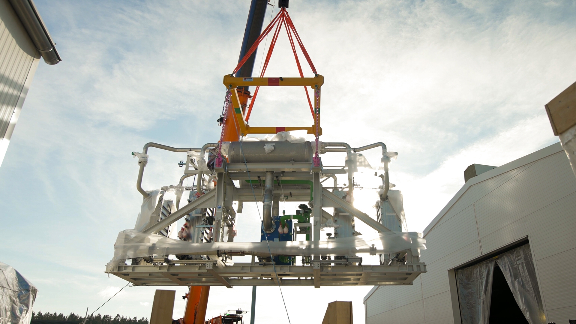 A crane lifting a large piece of electrolyzer equipment.